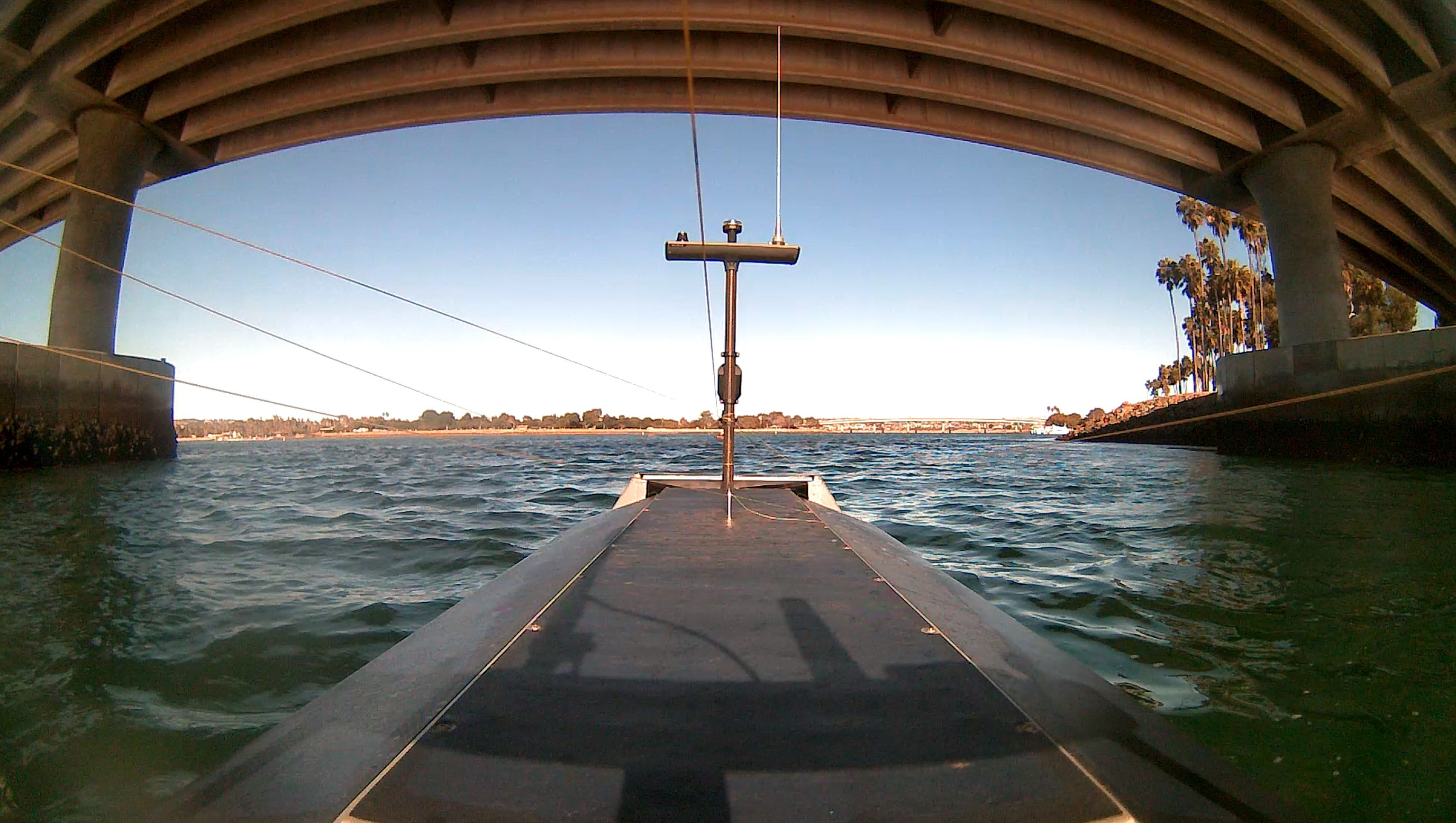 A forward-facing view from an autonomous surface vessel (ASV) navigating under a bridge, capturing real-time environmental data. Equipped with high-resolution vision systems for marine infrastructure inspection, hydrographic surveying, and maritime surveillance, the ASV operates autonomously in coastal waters.