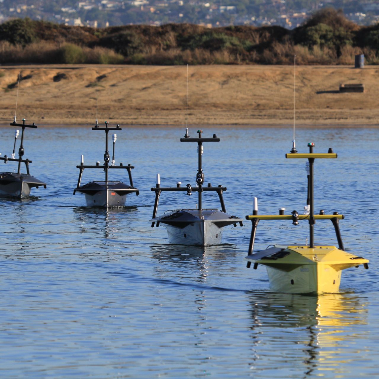 A fleet of autonomous surface vessels (ASVs) navigating coastal waters, equipped with advanced sensor arrays and vision systems for ocean mapping, environmental monitoring, and maritime surveillance. These unmanned platforms support real-time data collection and remote operations in marine research and defense applications.